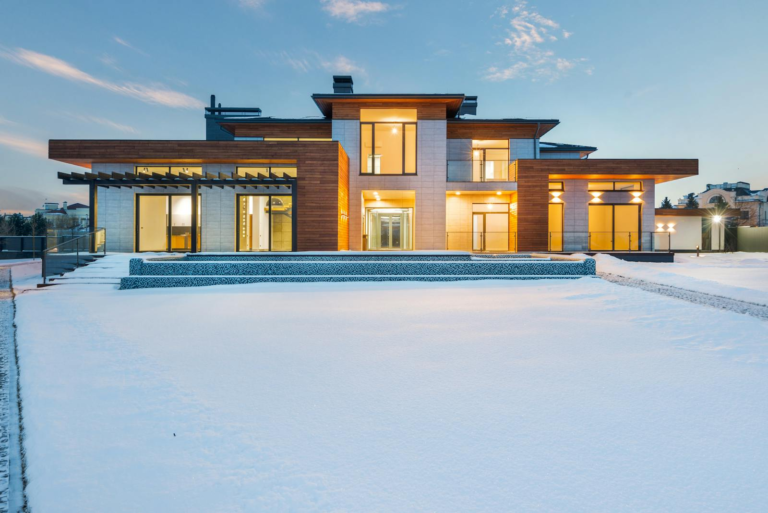 Contemporary luxury villa with modern design illuminated during winter with surrounding snow.